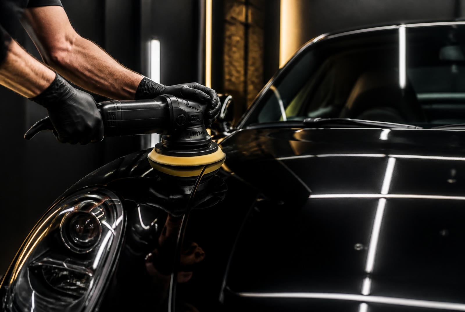 A specialist machine-polishing a black car